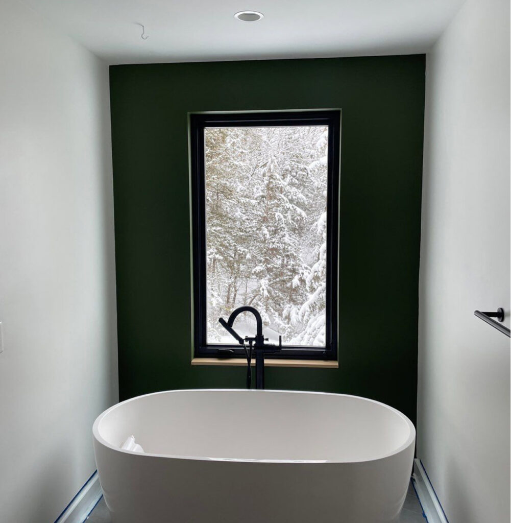 green accent wall in white bathroom with bath tub