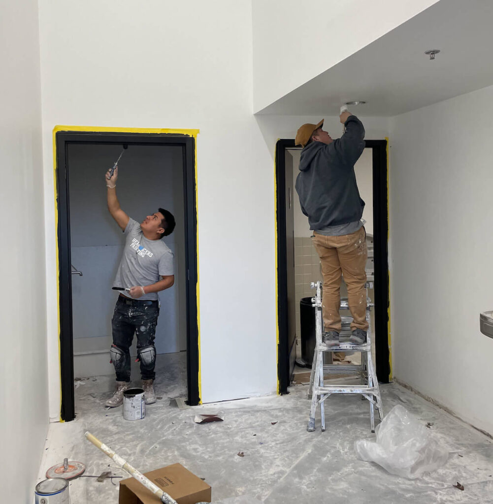 two men painting an office building.